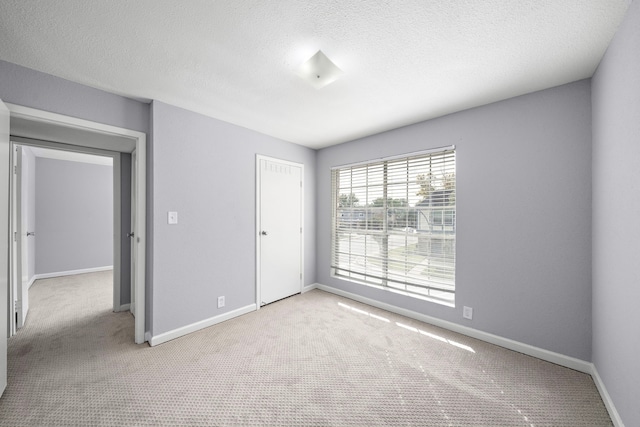 unfurnished bedroom with light carpet, a textured ceiling, and a closet