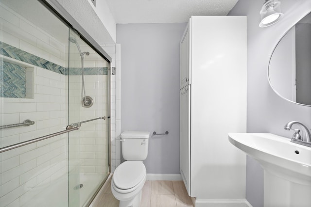 bathroom with toilet, sink, a textured ceiling, and walk in shower