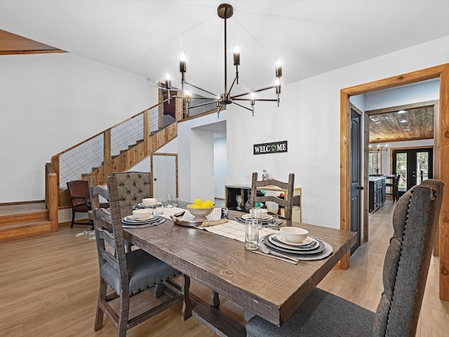 dining area with a chandelier, french doors, and light hardwood / wood-style flooring