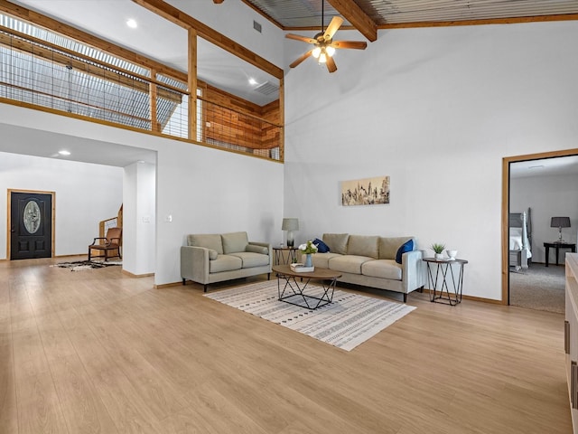 living room with beamed ceiling, light wood-type flooring, high vaulted ceiling, and ceiling fan