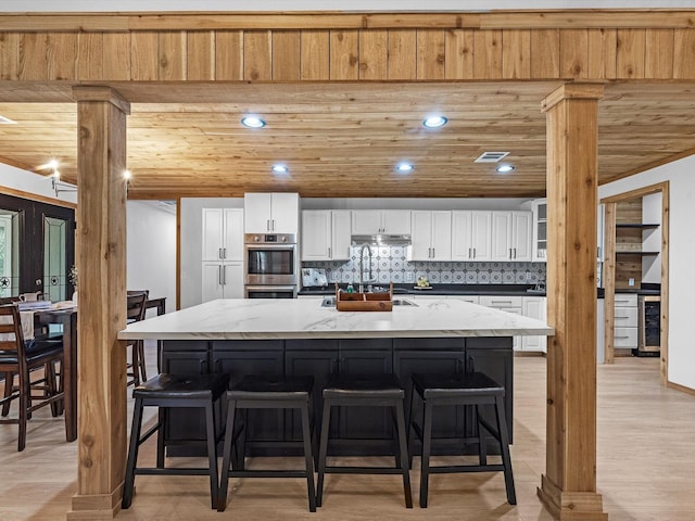 kitchen with a spacious island, light stone counters, and white cabinetry