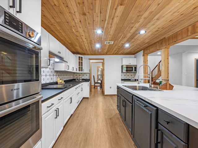 kitchen with appliances with stainless steel finishes, white cabinetry, wooden ceiling, and sink