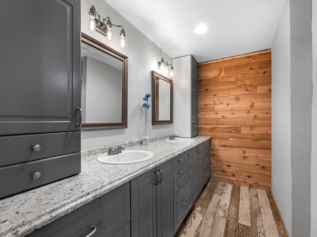 bathroom with hardwood / wood-style floors, vanity, and wood walls