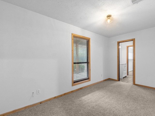 carpeted spare room with a textured ceiling