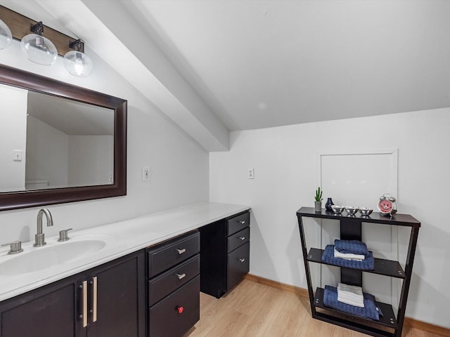 bathroom with hardwood / wood-style floors, vanity, and vaulted ceiling