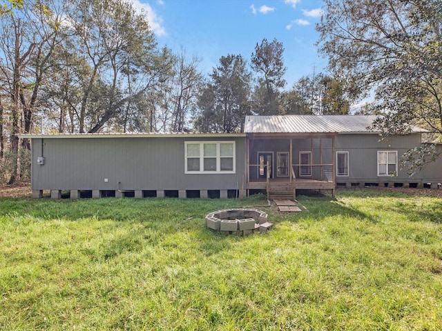 back of house featuring a lawn and an outdoor fire pit