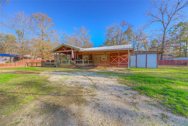 view of front facade featuring an outbuilding, a front lawn, and covered porch