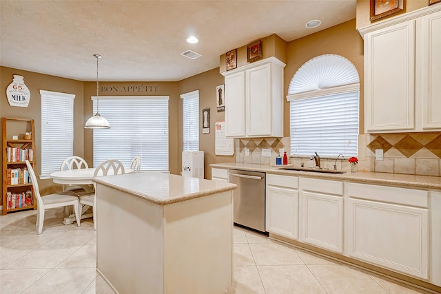 kitchen with sink, hanging light fixtures, stainless steel dishwasher, decorative backsplash, and light tile patterned floors