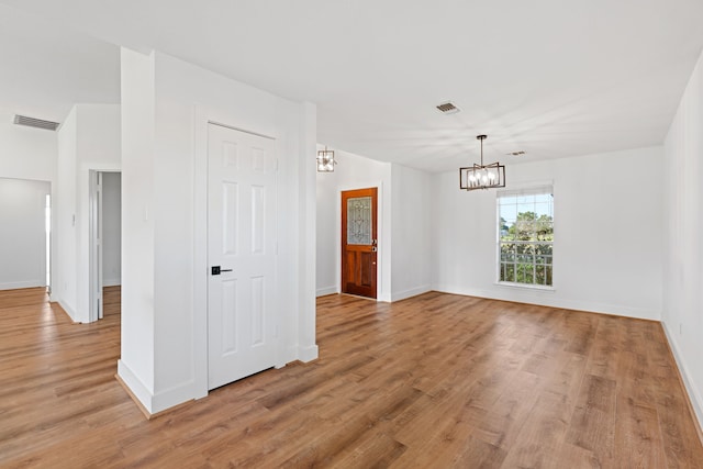 spare room featuring light hardwood / wood-style flooring and an inviting chandelier