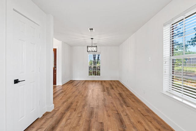 unfurnished dining area with hardwood / wood-style flooring and an inviting chandelier