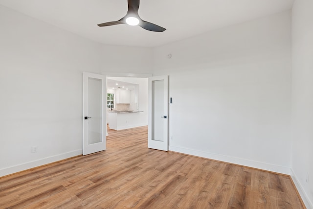 spare room with ceiling fan, light wood-type flooring, a towering ceiling, and french doors