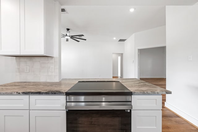 kitchen featuring backsplash, stainless steel range with electric cooktop, white cabinets, ceiling fan, and kitchen peninsula