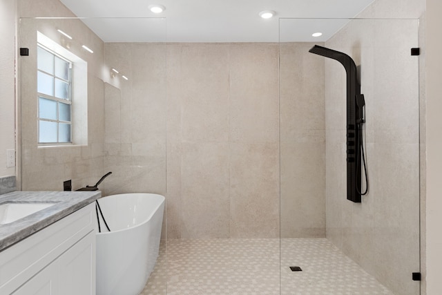 bathroom featuring vanity, shower with separate bathtub, and tile walls