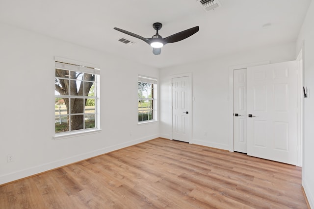 unfurnished bedroom with ceiling fan, two closets, and light wood-type flooring