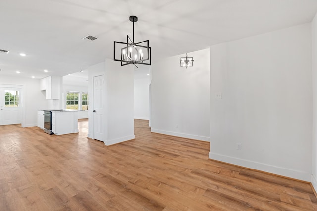 unfurnished living room featuring light hardwood / wood-style floors and an inviting chandelier