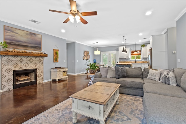 living room with sink, a fireplace, french doors, ceiling fan, and ornamental molding