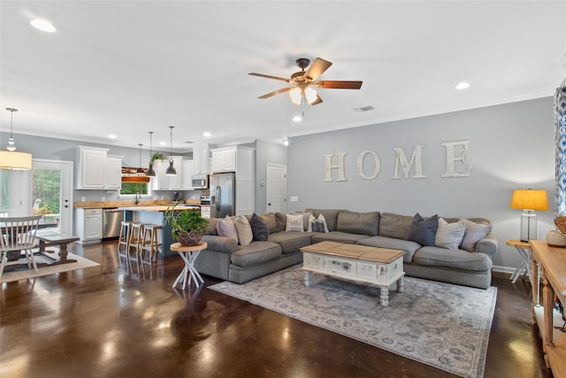 living room with ceiling fan and ornamental molding