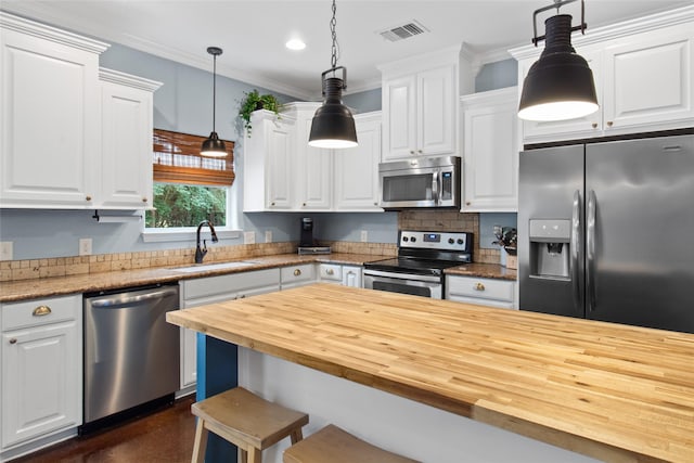 kitchen featuring decorative light fixtures, stainless steel appliances, butcher block counters, and sink