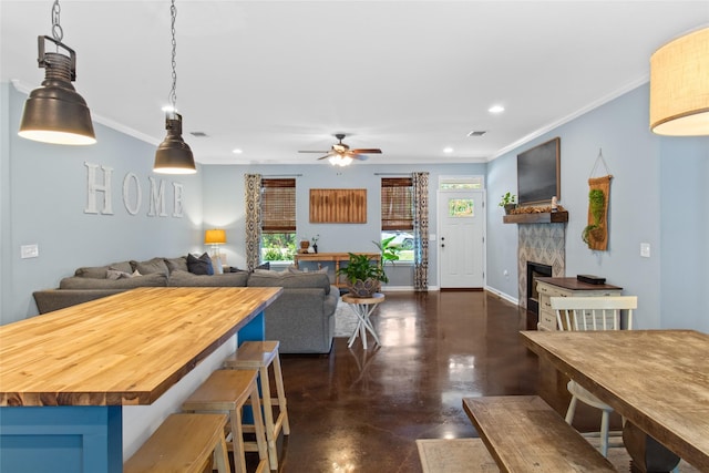 interior space featuring wooden counters, a tile fireplace, ceiling fan, and ornamental molding