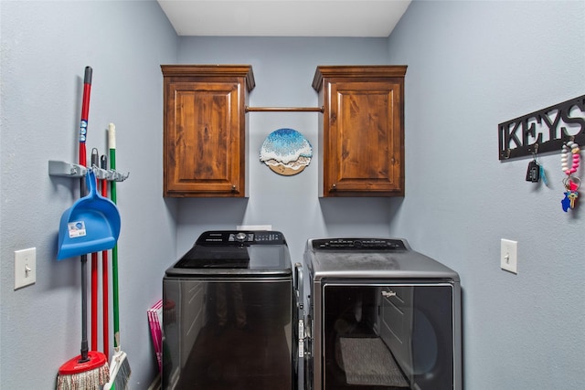 laundry area featuring washing machine and clothes dryer and cabinets