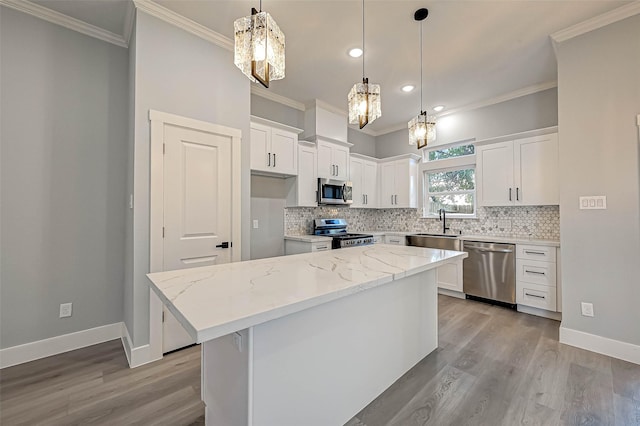 kitchen featuring stainless steel appliances, a kitchen island, light stone counters, decorative backsplash, and white cabinets