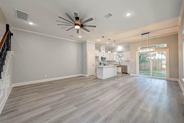 unfurnished living room with light wood-type flooring, ceiling fan, crown molding, and sink