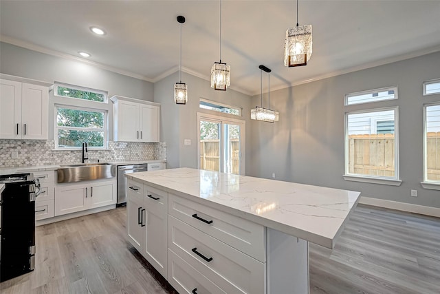 kitchen featuring a center island, white cabinets, sink, stainless steel dishwasher, and decorative light fixtures