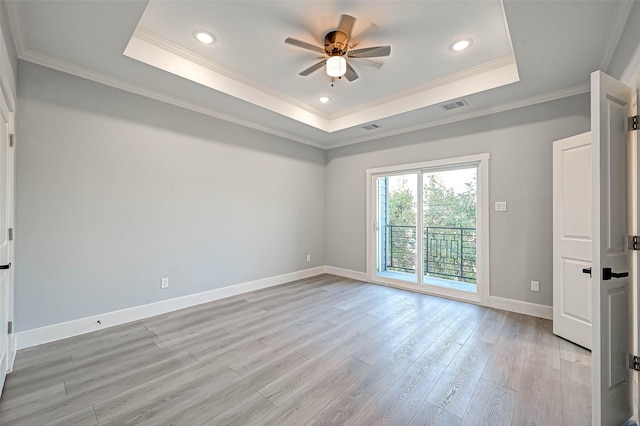 empty room with ornamental molding, a tray ceiling, ceiling fan, and light hardwood / wood-style floors