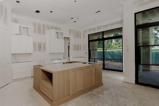 kitchen with a large island, light brown cabinets, white cabinets, and ornamental molding