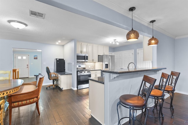 kitchen with white cabinetry, kitchen peninsula, pendant lighting, a kitchen bar, and appliances with stainless steel finishes