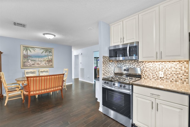 kitchen featuring white cabinets, decorative backsplash, dark wood-type flooring, and appliances with stainless steel finishes