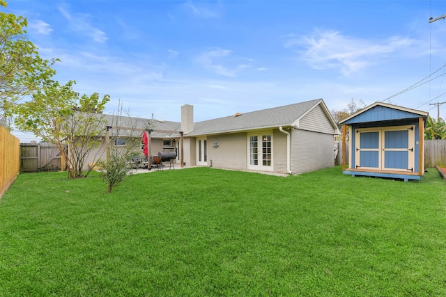 back of property featuring a yard, a patio, and a storage unit