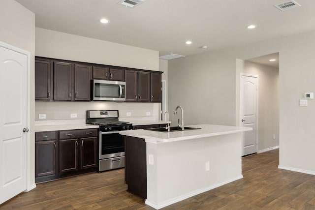 kitchen featuring a kitchen island with sink, sink, dark hardwood / wood-style floors, appliances with stainless steel finishes, and dark brown cabinetry