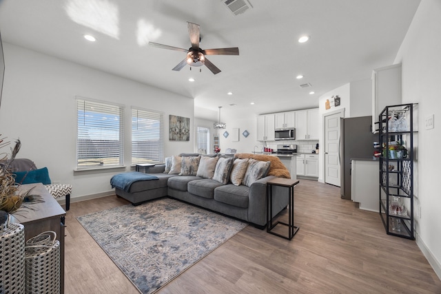 living area with a ceiling fan, recessed lighting, visible vents, and wood finished floors