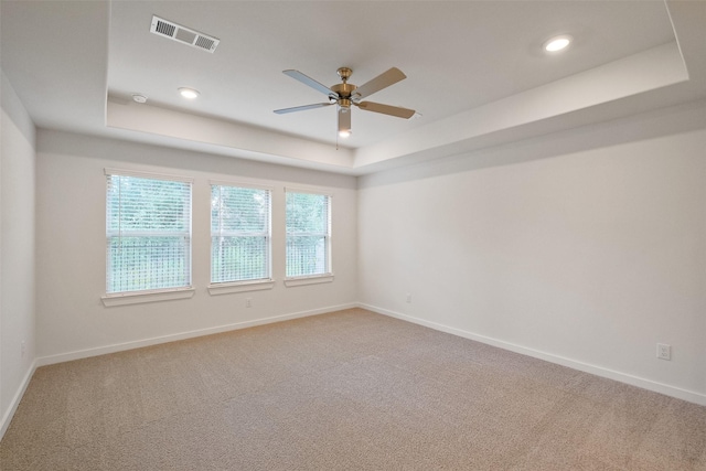 carpeted spare room featuring a raised ceiling and ceiling fan