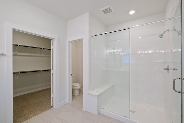 bathroom with tile patterned flooring, a shower with shower door, and toilet