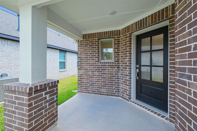 view of exterior entry featuring a porch and central AC