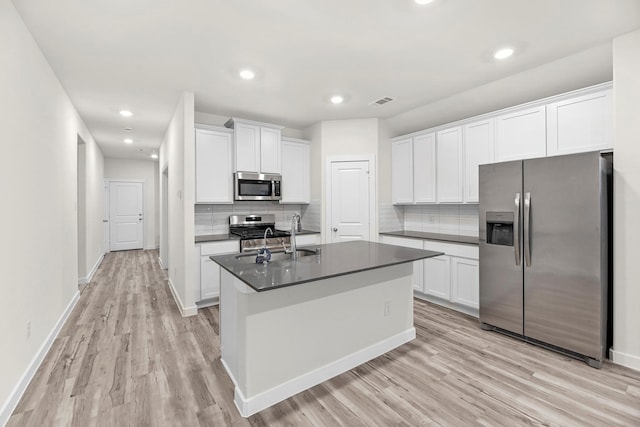 kitchen with white cabinets, stainless steel appliances, a kitchen island with sink, and sink