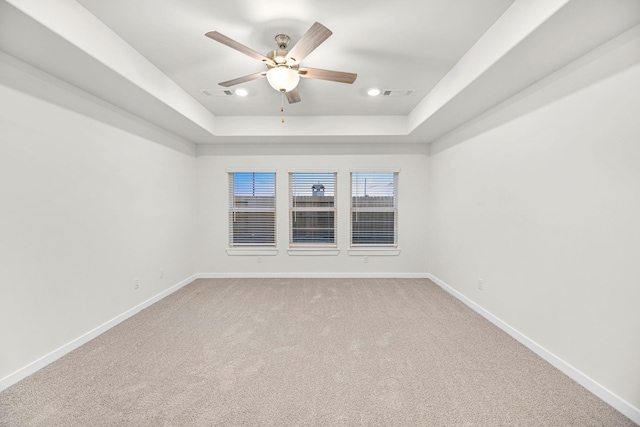 empty room featuring carpet flooring, a raised ceiling, and ceiling fan