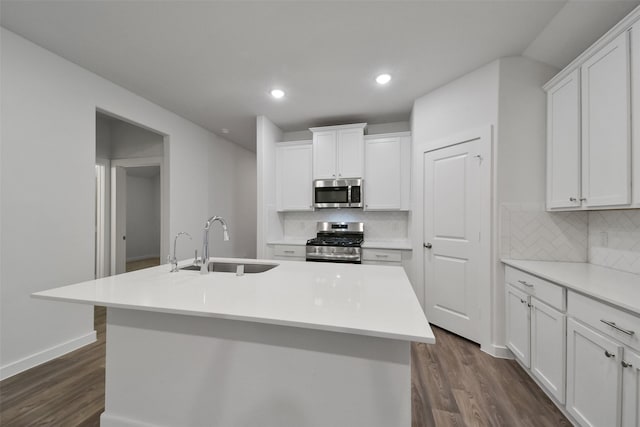 kitchen featuring dark hardwood / wood-style floors, white cabinetry, sink, stainless steel appliances, and a center island with sink