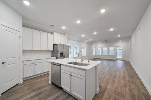 kitchen with white cabinetry, stainless steel appliances, sink, and a center island with sink