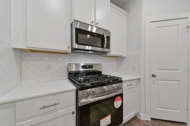 kitchen with white cabinetry, appliances with stainless steel finishes, tasteful backsplash, and hardwood / wood-style flooring