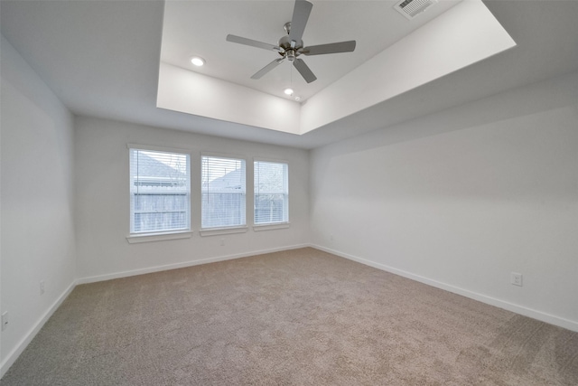 carpeted empty room with ceiling fan and a tray ceiling