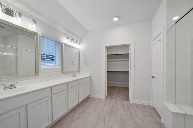 bathroom featuring a shower with door and vanity