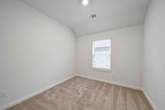 carpeted empty room featuring vaulted ceiling