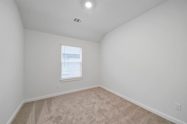 carpeted empty room with vaulted ceiling