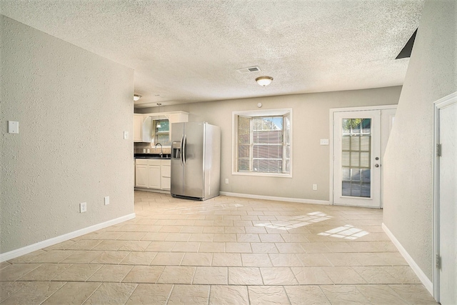 unfurnished living room featuring sink and a textured ceiling