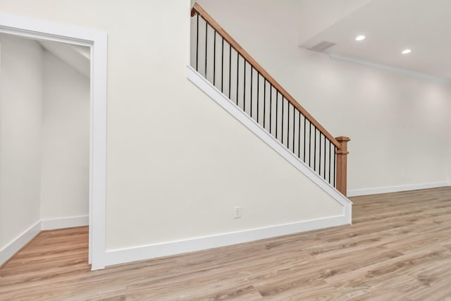 staircase with wood-type flooring and crown molding