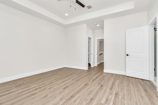 unfurnished bedroom with a tray ceiling, ceiling fan, and light wood-type flooring