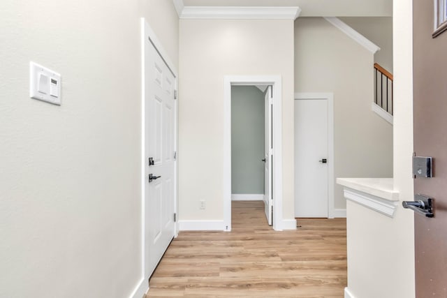 hall with light hardwood / wood-style floors and ornamental molding